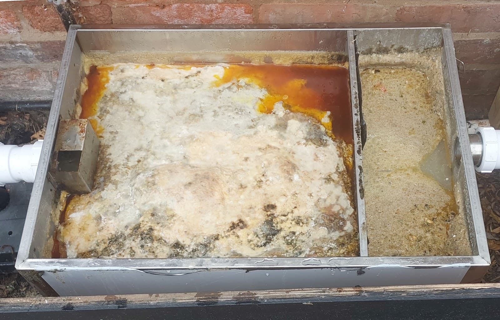 Grease trap before cleaning with heavy grease build-up visible inside the unit